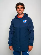Parka azul con capucha, cierre frontal con cremallera y logo del Club Nacional de Football en el pecho.