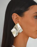 Aros colgantes plateados con forma geométrica irregular y diseño texturizado.