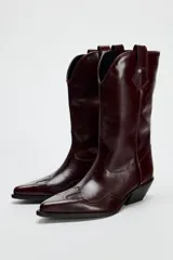 Bota de cuero color bordó, estilo cowboy, con puntera marcada y tiradores laterales.