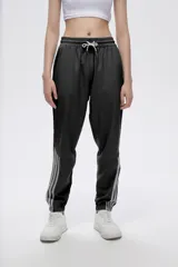 Pantalón de jogging negro con cintura elástica ajustable con cordón y tres rayas verticales grises a lo largo de la pierna.