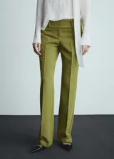 Pantalón de vestir verde oliva de tiro bajo y corte acampanado. Con trabillas, bolsillos traseros de ribete y cierre oculto de botón, gancho y cremallera.