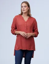 Blusa de crepe color terracota, con cuello en V, abertura frontal con botones y mangas largas regulables.