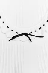 Camiseta blanca de canalé con escote redondo, manga corta y detalle de volantes con cordón negro a contraste.