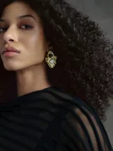 Pendientes metálicos con diseño en relieve de forma orgánica, decorados con una perla natural y una cuenta oscura. Poseen cierre de broche.