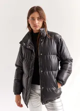 Campera puffer negra de cuero sintético, con cuello alto, cierre frontal con cremallera y botones a presión, y bolsillos laterales.