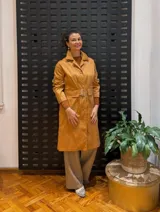 Gabardina color mostaza con cuello camisero, cierre frontal con botones y cinturón con hebilla.