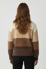 Sweater de tejido de punto con diseño de bloques horizontales en tonos tierra: blanco crema, beige claro, camel y marrón oscuro. Presenta cuello redondo y puños y ruedo acanalados.