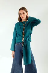 Blusa blanca de lino con escote en V cruzado, mangas largas y lazo en la cintura.