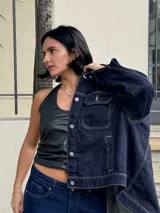 Campera de jean azul oscuro con costuras en hilo ocre, corte recto, cuello clásico, bolsillos frontales con solapa y cierre con botones metálicos.