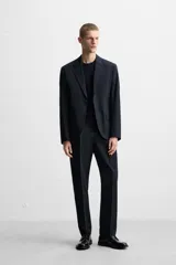 Pantalón de vestir azul marino, de corte recto, con pinzas frontales, bolsillos laterales y traseros con doble vivo y botón.