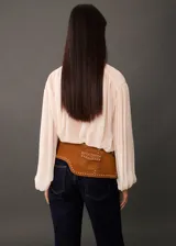 Blusa color crema de mangas largas abullonadas, con lazo en el cuello y tejido semitransparente.