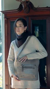 Bandolera beige de símil cuero con dos bolsillos frontales con cierre, un bolsillo trasero, tres bolsillos internos y correa larga regulable.