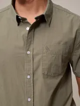 Camisa de algodón blanca de manga corta, con cuello abotonado y botones frontales.