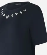 Remera negra de viscosa con cuello redondo y mangas cortas. Presenta apliques de strass en el escote.