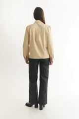 Camisa blanca de manga larga con cuello clásico y cierre frontal con botones. Presenta detalles de bordado calado a lo largo del frente.