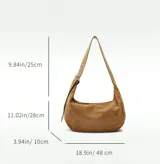 Bolso marrón de gamuza con forma de media luna y tachas plateadas. Tiene correa de hombro ajustable con hebilla metálica y cierre superior con cremallera.