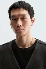 Chaleco negro de punto con cuello en V y cierre frontal con cremallera. Tiene bolsillos de ribete en la cadera y un corte relajado.