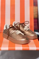 Championes de cuero color cobre con doble cordón, suela marrón y detalles en blanco.