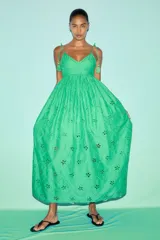 Vestido largo verde con breteles finos y escote en V. Presenta bordados florales y detalles de broderie en todo el vestido. Tiene corte en la cintura y falda con vuelo.