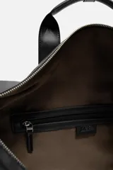 Bolso de viaje negro con compartimento principal con cierre de cremallera, bolsillo interior con cremallera, detalle de arnés en la parte frontal, dos asas de mano y asa de hombro ajustable y extraíble.