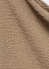 Camiseta color beige con textura, cuello asimétrico y manga larga. Diseño entallado.
