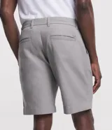 Bermuda de hombre color gris claro, corte slim, con trabillas en la cintura, cierre con botón y cremallera, lazo interno, bolsillos delanteros y traseros, y tejido texturizado.