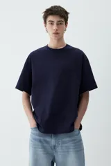 Remera azul marino de punto de algodón pesado, con cuello redondo ribeteado, hombros caídos y bajo recto. Corte holgado.