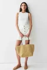 Minifalda evasé de denim color blanco, de tiro alto con botonadura frontal y bolsillos decorativos con solapa y botón.