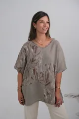 Blusa color visón con estampado de hojas en tonos marrones, de corte holgado y mangas cortas.