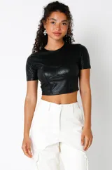 Crop top negro de cuero sintético, elastizado y forrado, con busto marcado estilo corset y mangas cortas.