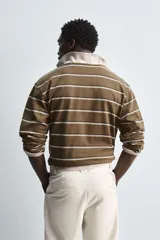 Camiseta marrón con rayas horizontales blancas y negras, de corte relaxed fit, cuello redondo amplio y mangas largas.