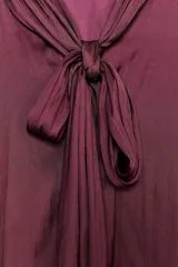 Blusa color borgoña de cuello redondo con lazada en el mismo tejido y manga larga acampanada.