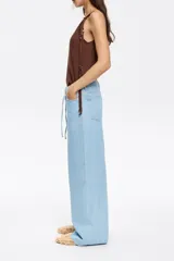 Pantalón largo de denim celeste, de corte wide leg, tiro bajo, con cinco bolsillos y cordón ajustable en la cintura.