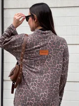 Sweater de punto con estampado animal print en tonos grises y marrones, cuello alto, corte holgado, más largo en la parte trasera y tajos laterales.