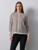 Blusa de gasa estampada a rayas verticales negras sobre fondo beige, marca Sioni. Espalda con abertura y botón. Manga larga con puño y botón.