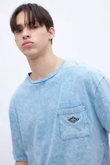 Remera celeste con efecto marmolado, bolsillo en el pecho con parche decorativo y arte en la espalda baja. De calce oversize y algodón lavado con textura extra suave.