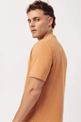 Remera de algodón color naranja claro con cuello redondo y manga corta. Presenta un pequeño estampado gráfico de temática playera en el pecho izquierdo.
