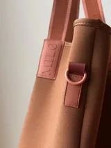 Bolso negro tipo tote de neopreno con bolsillo interno de red, sobre haciendo juego y gancho para sujetarlo.