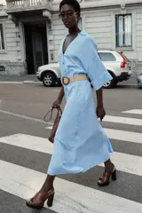 Vestido midi celeste a rayas verticales blancas, con cuello solapa, escote pico y mangas cortas con vuelta. Incluye cinturón de soga con hebilla circular.