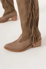 Bota texana de caña alta color visón, 100% cuero hecha a mano en Uruguay, con cierre lateral y taco de 5,5 cm. Tiene flecos en los costados internos.
