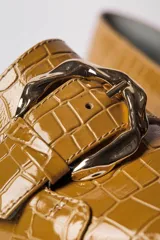 Zapato de cuero vacuno textura croco color mostaza, con detalle de hebilla dorada y taco bajo.