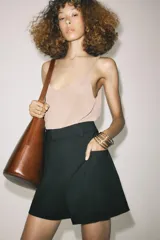 Shorts de tiro alto color negro, con cintura con trabillas, bolsillos laterales y cierre frontal con cremallera y ganchos metálicos.