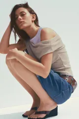 Camiseta blanca con musculosa gris superpuesta con escote asimétrico.