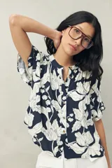 Camisa azul marino con estampado de flores blancas, de manga corta, silueta relajada y cuello mao.