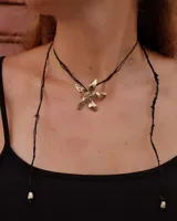 Collar artesanal con dije de flor plateada, realizado con hilo de seda natural teñido a mano.