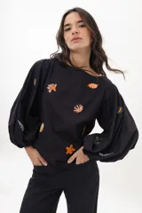 Blusa negra de algodón con escote a la base y mangas abullonadas. Presenta bordados artesanales con motivos marinos.