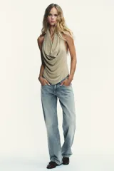 Pantalón de jean celeste claro, de tiro bajo, corte wide leg y largo hasta el tobillo. Tiene cinco bolsillos, cierre frontal con cremallera y botón metálico.