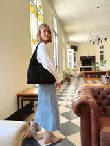 Bolso tipo tote bag negro de cuero, con costuras a la vista y manijas cortas.