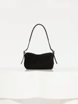 Mini bolsa negra realizada en cuero vacuno con acabado desgastado, forro en tejido jacquard y bolsillo interior con cierre.