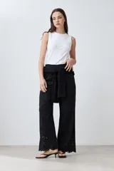 Pantalón negro de corte amplio con bordado de boderie y lazo de ajuste en la cintura.